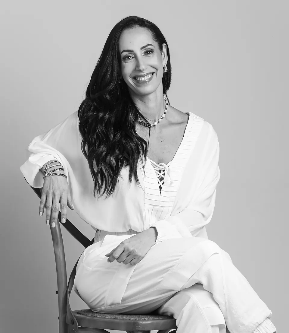 Dra. Denise de Carvalho sentada em uma cadeira de madeira, em foto de estúdio em preto e branco